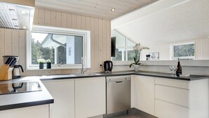 Une cuisine moderne avec des meubles blancs, un plan de travail noir et une fenêtre donnant sur l’extérieur.