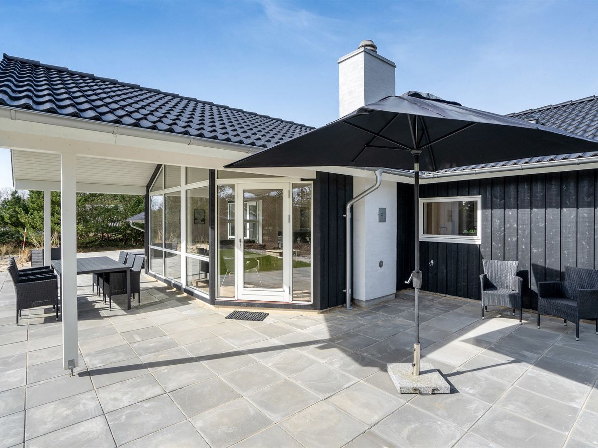 A covered patio with outdoor furniture, a glass door entrance, and a chimney.