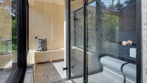 Een moderne spa ruimte met een houten bank, een glazen deur en uitzicht op het groen.