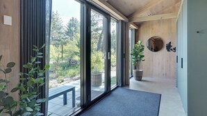 Een modern interieur met grote schuiframen naar een balkon, een houten plafond en een potplant.