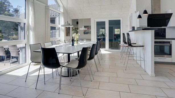 Une cuisine moderne dotée d’un grand espace à manger, bénéficiant d’un éclairage naturel abondant et offrant une vue sur l’extérieur.