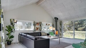 Un salon moderne avec un canapé d’angle, une table à manger et une cheminée.