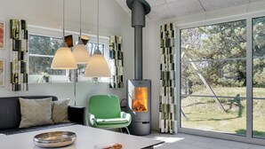 Un salon moderne avec une grande fenêtre, un fauteuil vert, un canapé et une table sur laquelle se trouvent un bol et une boîte.