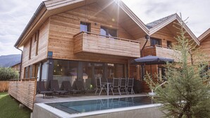 Uma chalé de madeira com piscina, área de estar ao ar livre e varanda.