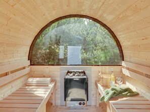 A sauna with wooden benches, a fireplace, and a large arched window overlooking a forest. - "Ingobald" - 1.5km from the sea by Interhome (Blåvand)