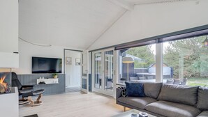Ein modernes Wohnzimmer mit einer Couch, einem Couchtisch, einem Kamin und einem Fernseher.
