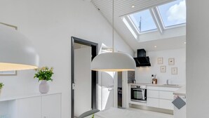 Eine moderne Küche mit Oberlichtern, weißen Schränken und einem Essbereich mit Tisch und Stühlen.