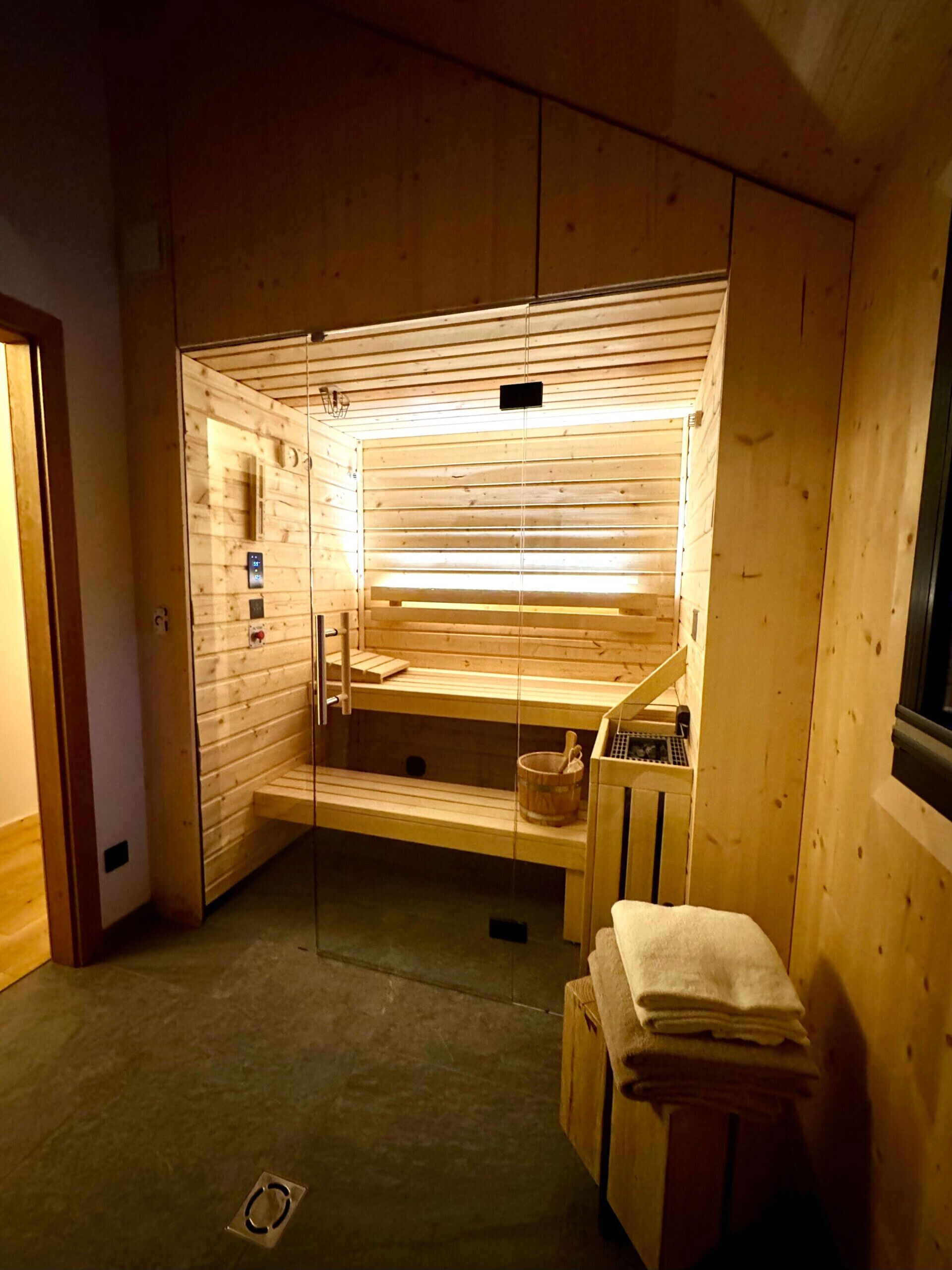 Un sauna con paredes y bancos de madera, un lavamanos pequeño y una pila de toallas.