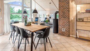 A modern kitchen with a wooden table, black chairs, and a brick accent wall. - "Ronna" - 2.2km from the sea by Interhome (Blåvand)