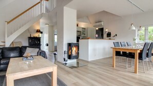 A modern living room with a fireplace, a dining area, and a staircase. - "Moa" - 800m from the sea by Interhome (Blåvand)