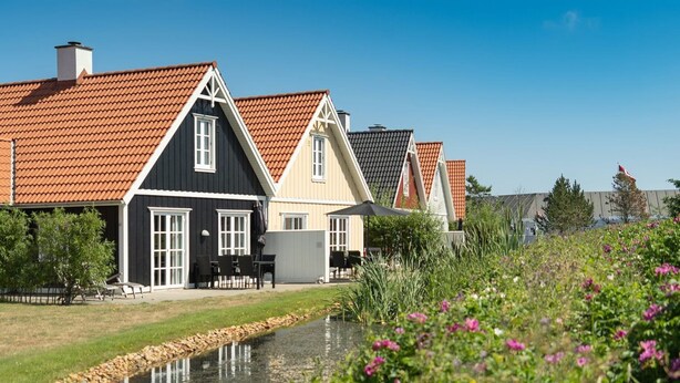 A row of houses with red-tiled roofs and a small pond in the foreground. - "Moa" - 800m from the sea by Interhome (Blåvand)
