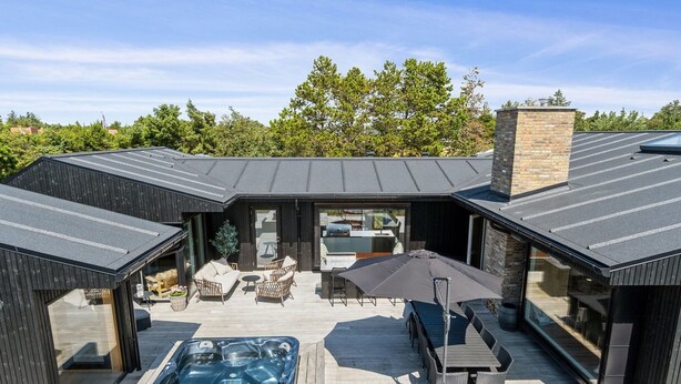 Un espace extérieur moderne, aménagé en terrasse, avec un jacuzzi, des sièges et une table couverte.