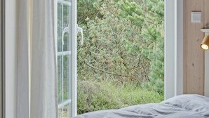 Un dormitorio con un ventanal grande, una cama y un aplique de pared.