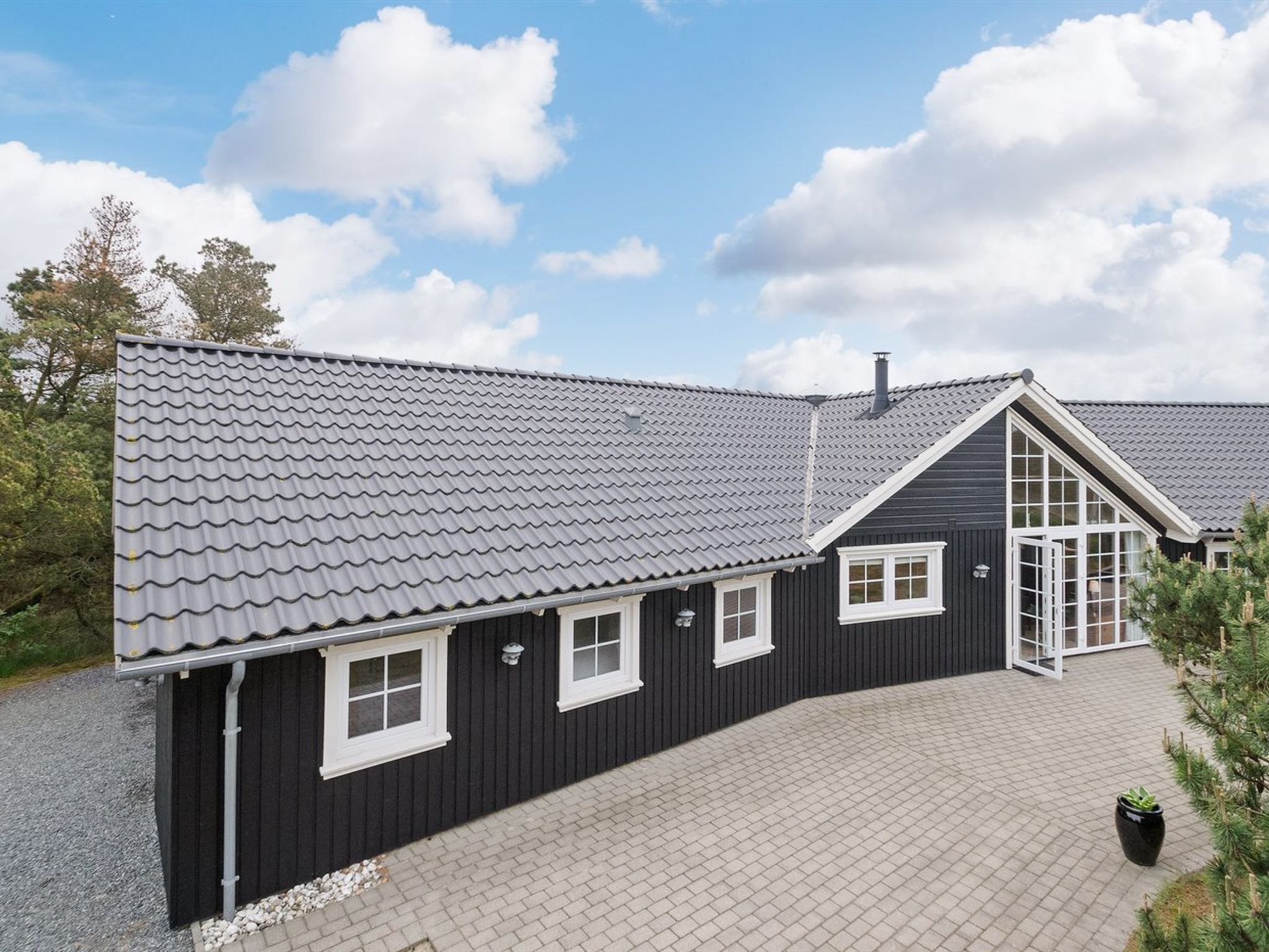 A two-story building with a grey tiled roof, black exterior walls, and white-framed windows.