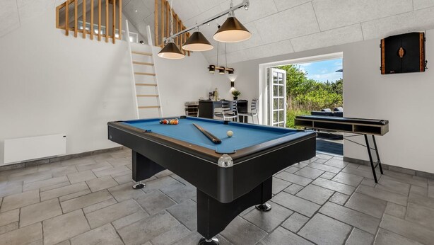 A modern indoor pool table with a wooden ladder and a billiards set.