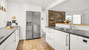 A modern kitchen with a stainless steel refrigerator, a Bosch dishwasher, and a stone backsplash.
