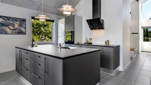 Una cocina moderna con una isla grande, luces colgantes y vistas al exterior.