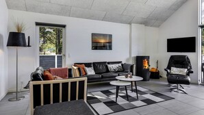 Una sala de estar moderna con un sofá de cuero negro, una mesita de centro y una chimenea.