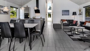 Una cocina moderna con una isla central, zona de comedor con sillas, un sofá y una mesa de centro.