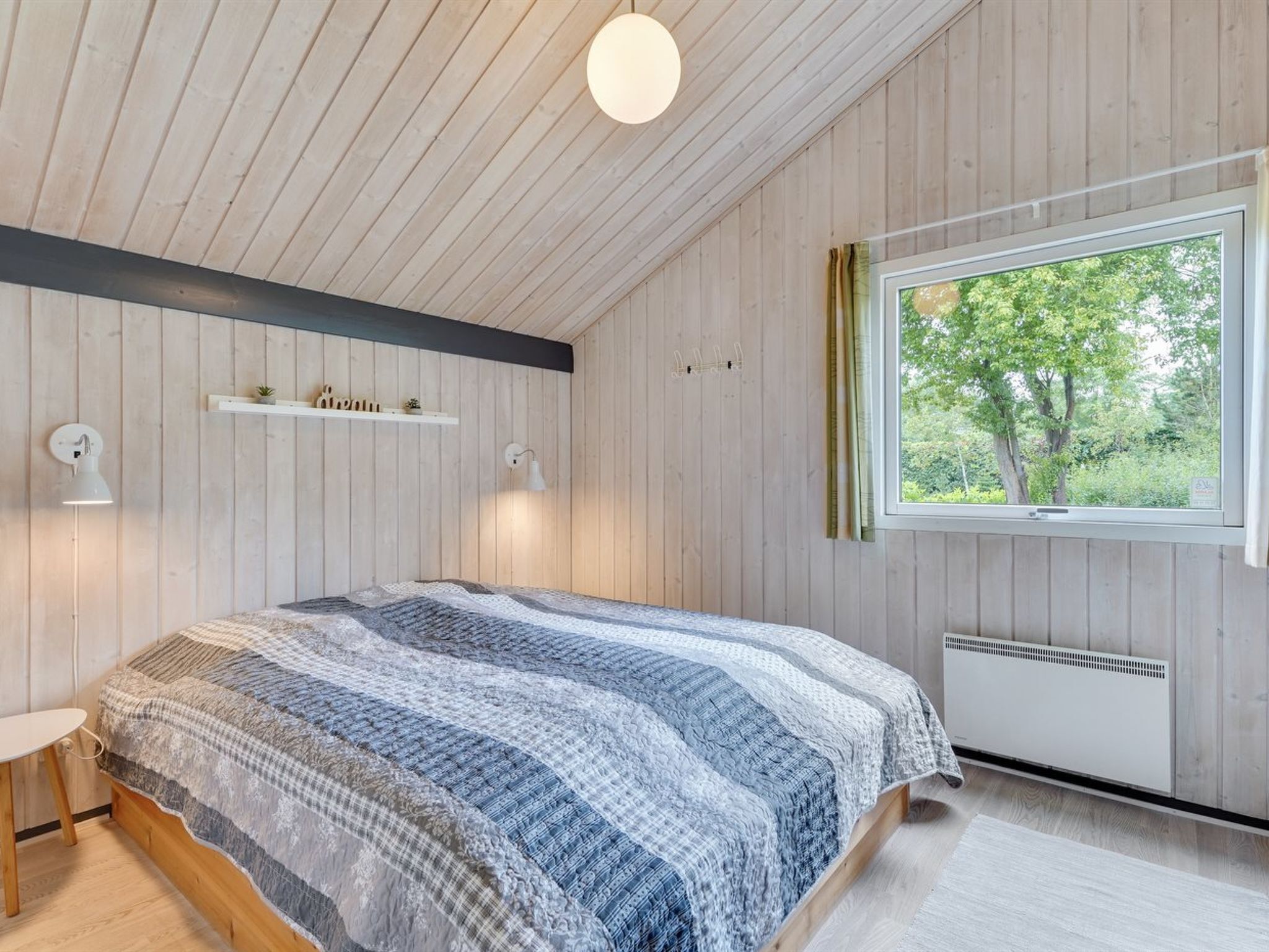 Een slaapkamer met een bed, nachtkastjes, een raam en een radiator.