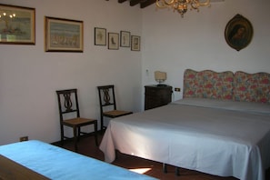 Une chambre à coucher avec un lit, deux chaises, une table de chevet et un lustre.