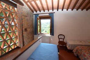 A room with a bed, a chair, a small table, and a window with curtains.
