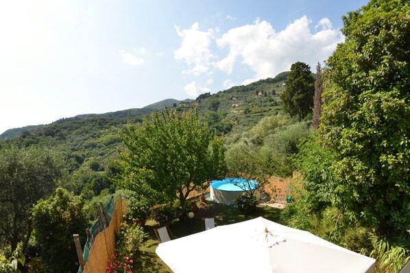 A garden with a swimming pool, surrounded by lush greenery and hills in the background.