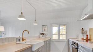 A modern kitchen with white cabinetry, a large sink, and a window providing natural light. - "Sine" - 500m from the sea by Interhome (Blåvand)