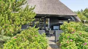 A modern house with a thatched roof, a patio with outdoor furniture, and a garden with flowering plants. - "Sine" - 500m from the sea by Interhome (Blåvand)