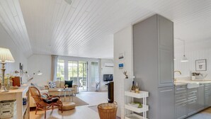 A spacious living area with a sofa, a coffee table, and a TV. There is a kitchen area with cabinets and a countertop. - "Sine" - 500m from the sea by Interhome (Blåvand)