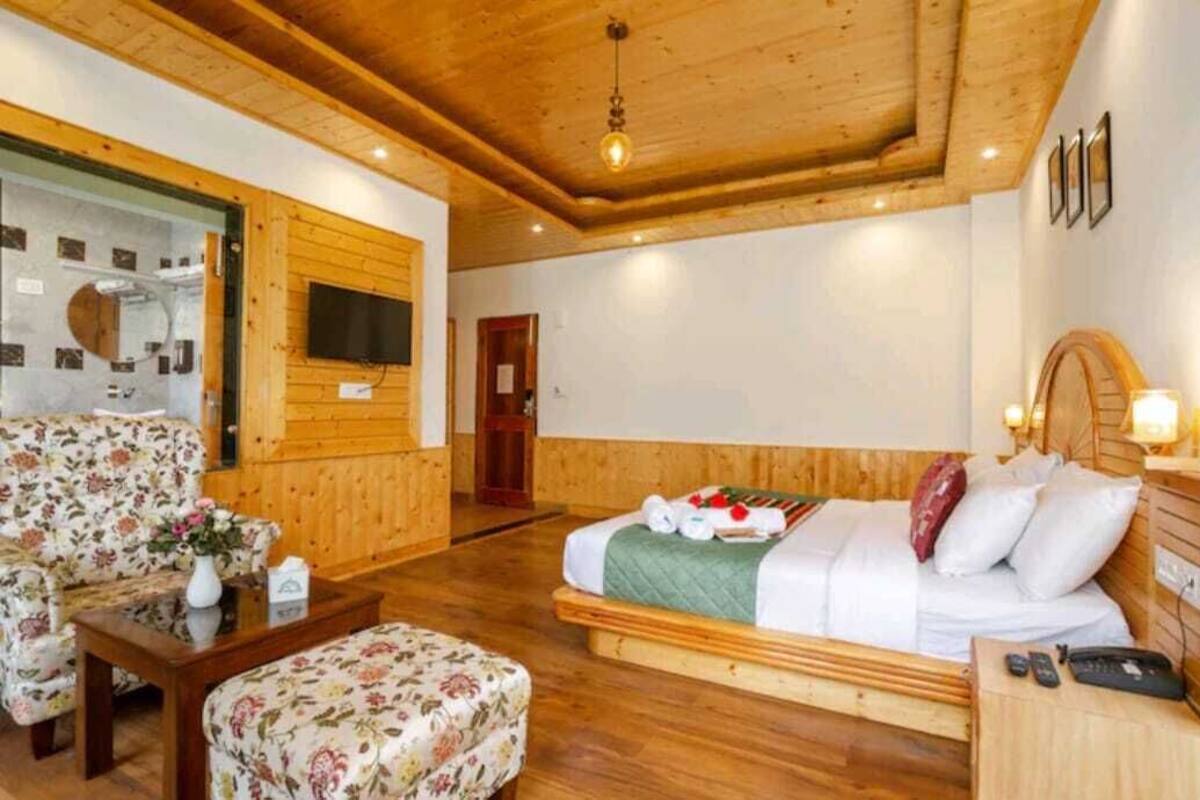 A wooden-floored room with a bed, a sofa, and a television.