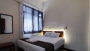 A neatly made bed with a headboard, a bedside table, and a window with curtains. - Hotel O Minso Inn Sepanjang (Wonosari)