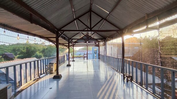 A covered walkway with a metal roof, railings, and a view of the landscape beyond. - Hotel O Minso Inn Sepanjang (Wonosari)