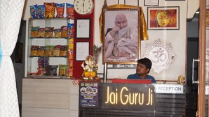Uma área de recepção com uma placa que diz "Jai Guru Ji" e um relógio na parede.