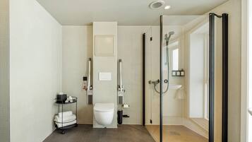 Ein modernes Badezimmer mit Toilette, einer Duschkabine aus Glas und einer kleinen Ablage für Toilettenartikel.
