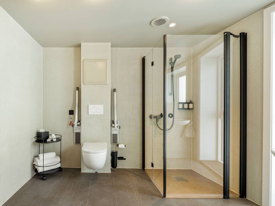 Ein modernes Badezimmer mit Toilette, einer Duschkabine aus Glas und einer kleinen Ablage für Toilettenartikel.