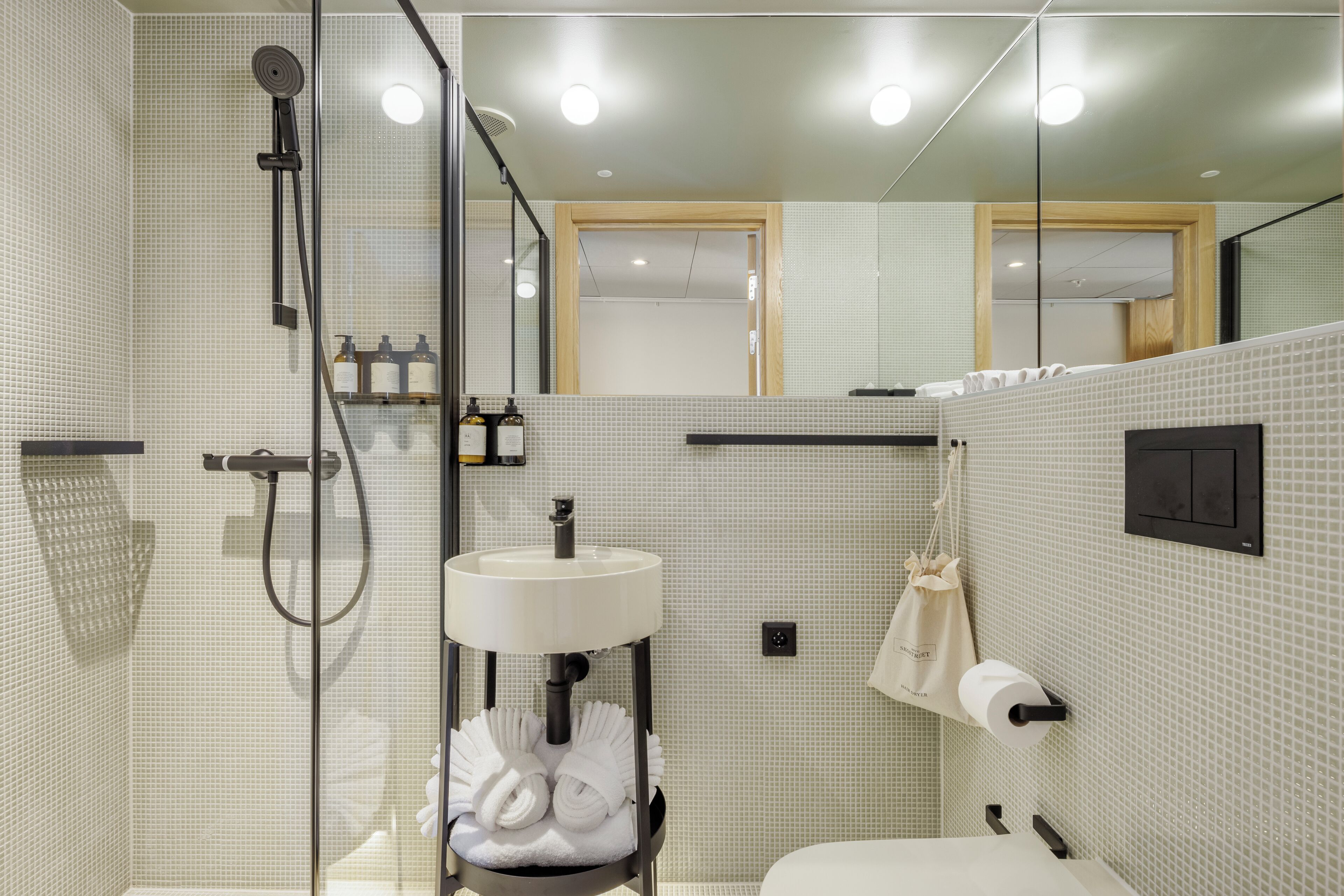 Une salle de bain moderne avec une douche à parois de verre, un lavabo blanc et un miroir.
