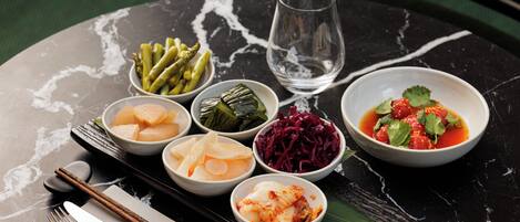 A table with various dishes, chopsticks, a glass, and cutlery.