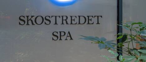 A sign for 'SKOSTREDET SPA' with a circular blue light above the text.
