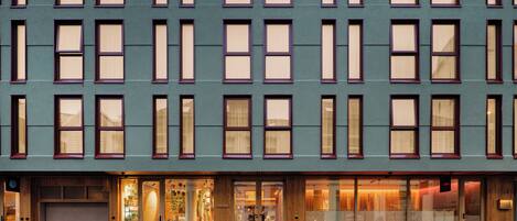 A multi-story hotel with a row of uniformly sized windows and a ground-level entrance with a wooden facade.