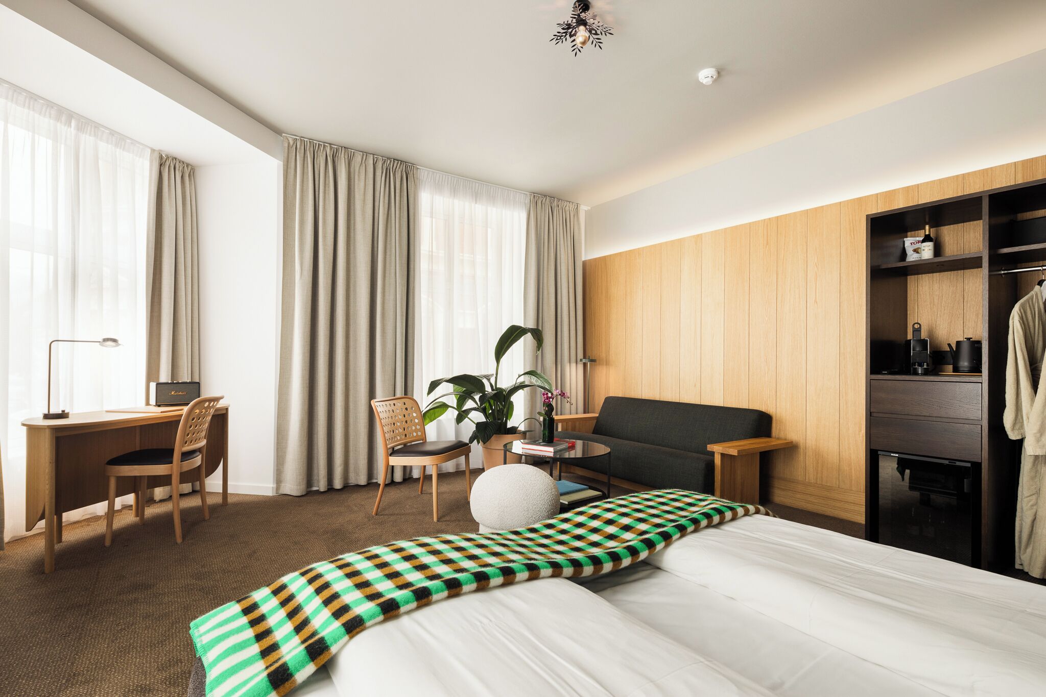 A hotel room with a bed, a desk, a chair, a sofa, a coffee table, and a wardrobe.
