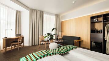 A hotel room with a bed, a desk, a chair, a sofa, a coffee table, and a wardrobe.