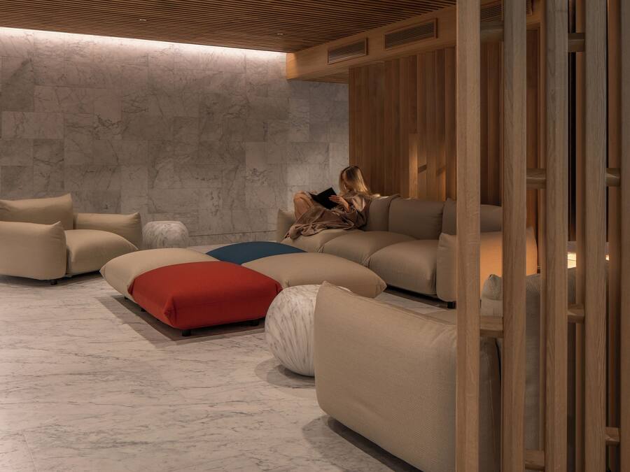 Un interior moderno con un sofá seccional, cojines rojos y blancos, y un techo de madera.
