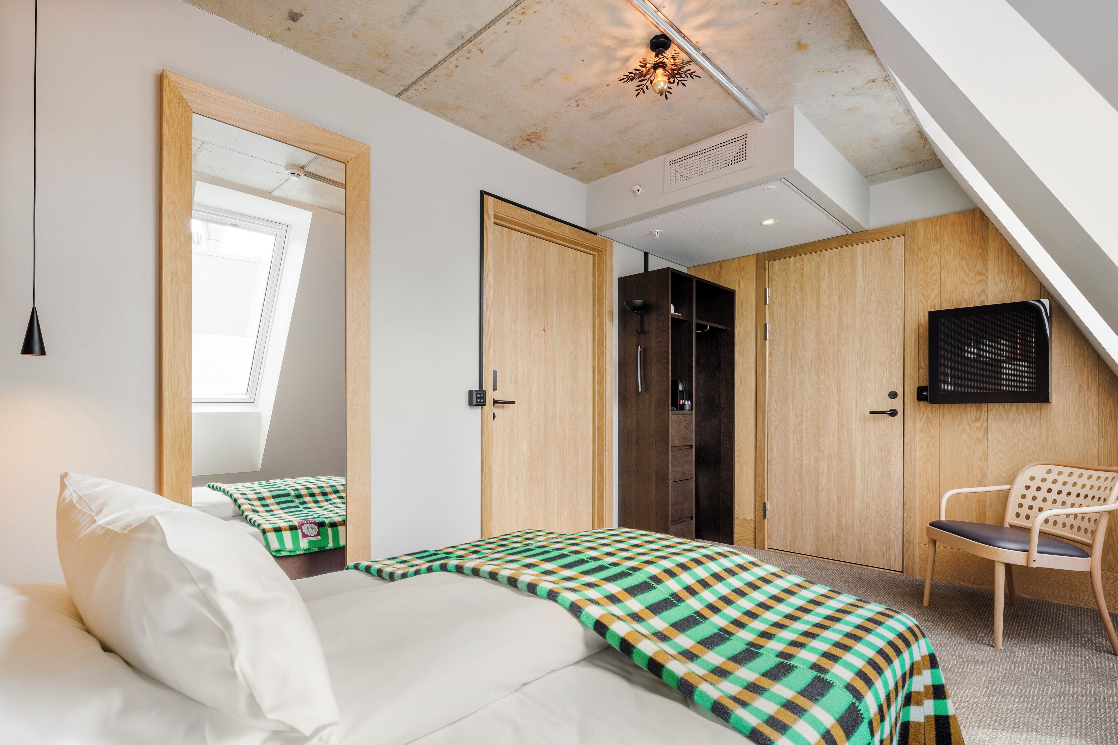 A bedroom with a bed, a chair, a wardrobe, and a television.