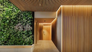 A modern hallway with a wooden slatted ceiling, a green plant wall, and a wooden panel wall. - Skostredet Hotel & Spa (Bergen)