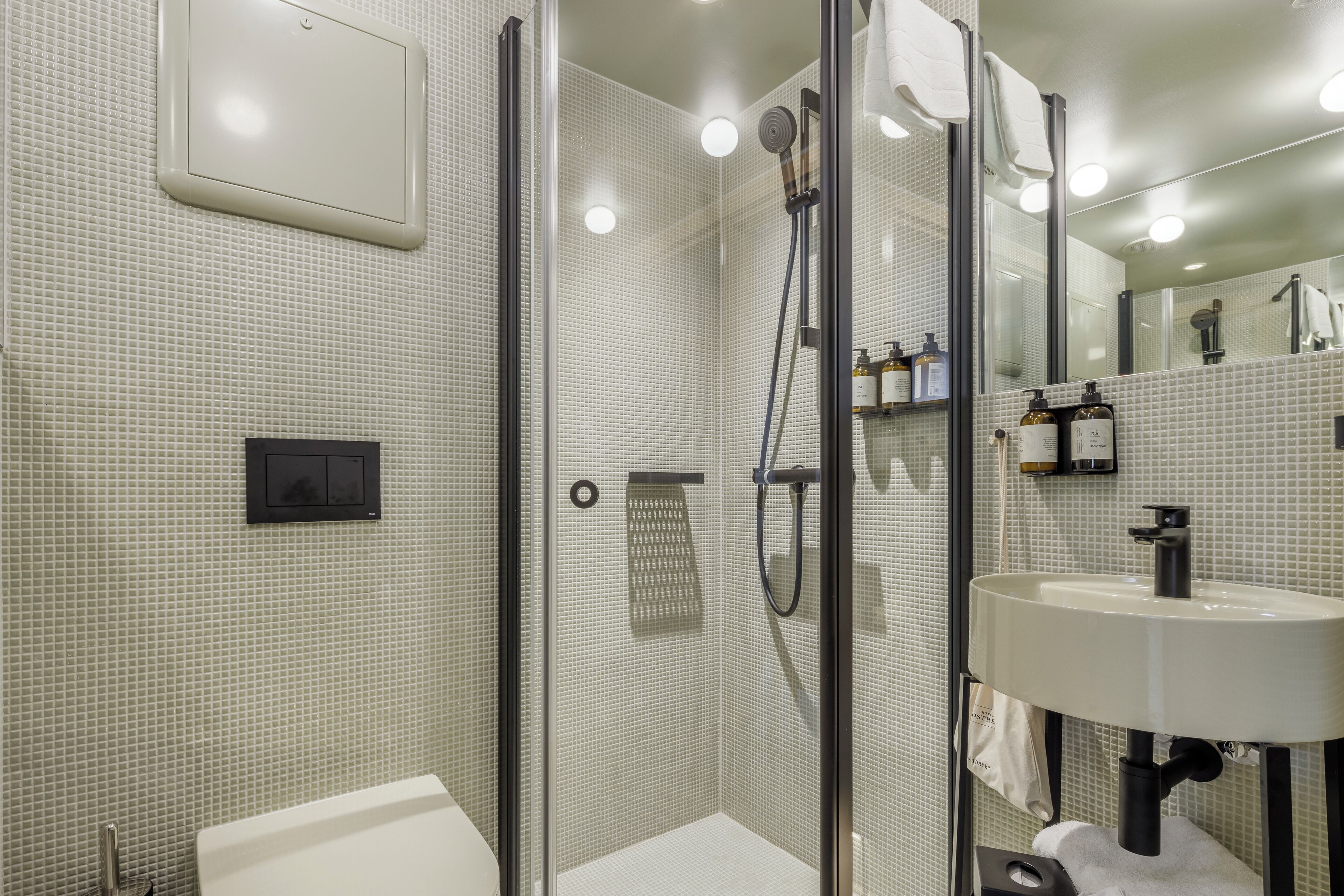 Une salle de bain moderne avec une douche à parois de verre, un lavabo blanc et un mur recouvert de carreaux.