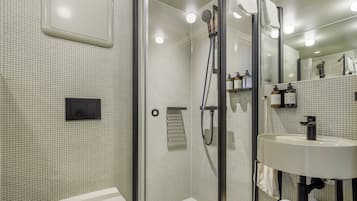 Un baño moderno con ducha de vidrio, lavamanos blanco y pared con azulejos.