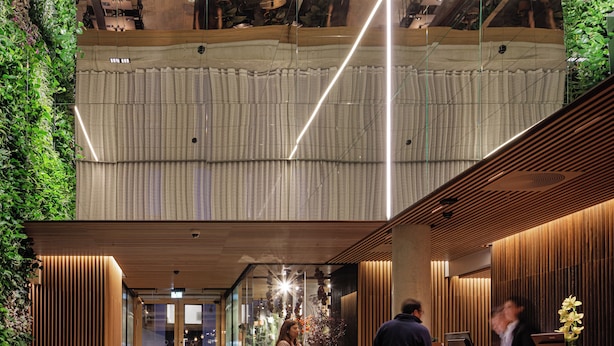 A modern lobby with a high ceiling, wooden paneling, and a green vertical garden. - Skostredet Hotel & Spa (Bergen)