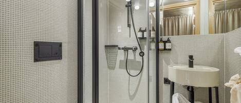 Un baño moderno con ducha envuelta en vidrio, un lavamanos blanco y un espejo.