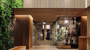 A modern interior with a wooden slatted ceiling, glass doors, and a plant wall. - Skostredet Hotel & Spa (Bergen)